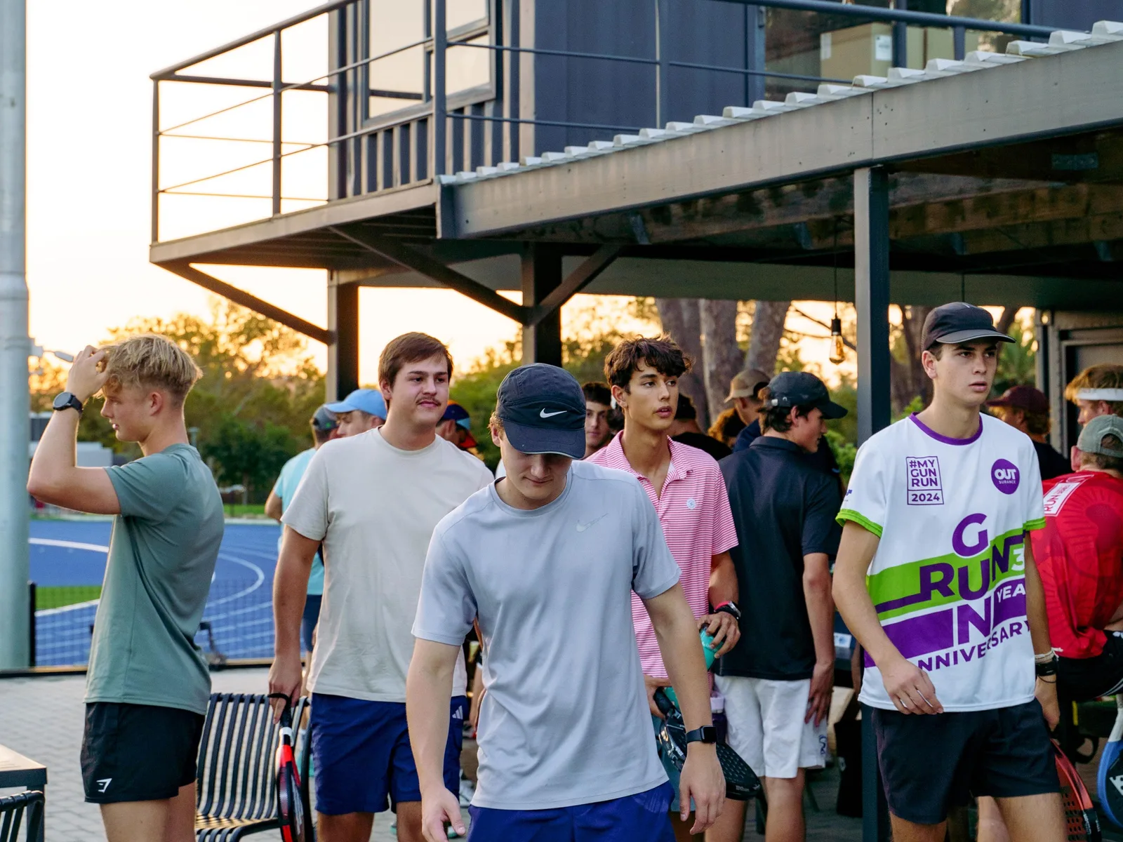 Players gathered with their rackets after a match, talking in the last of the evening light