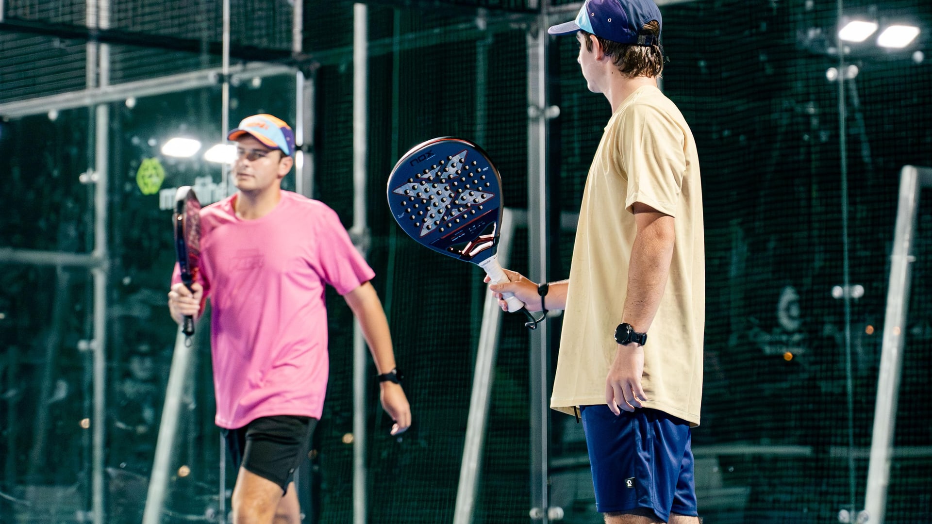 Two players talking on court, rackets in hand, between games
